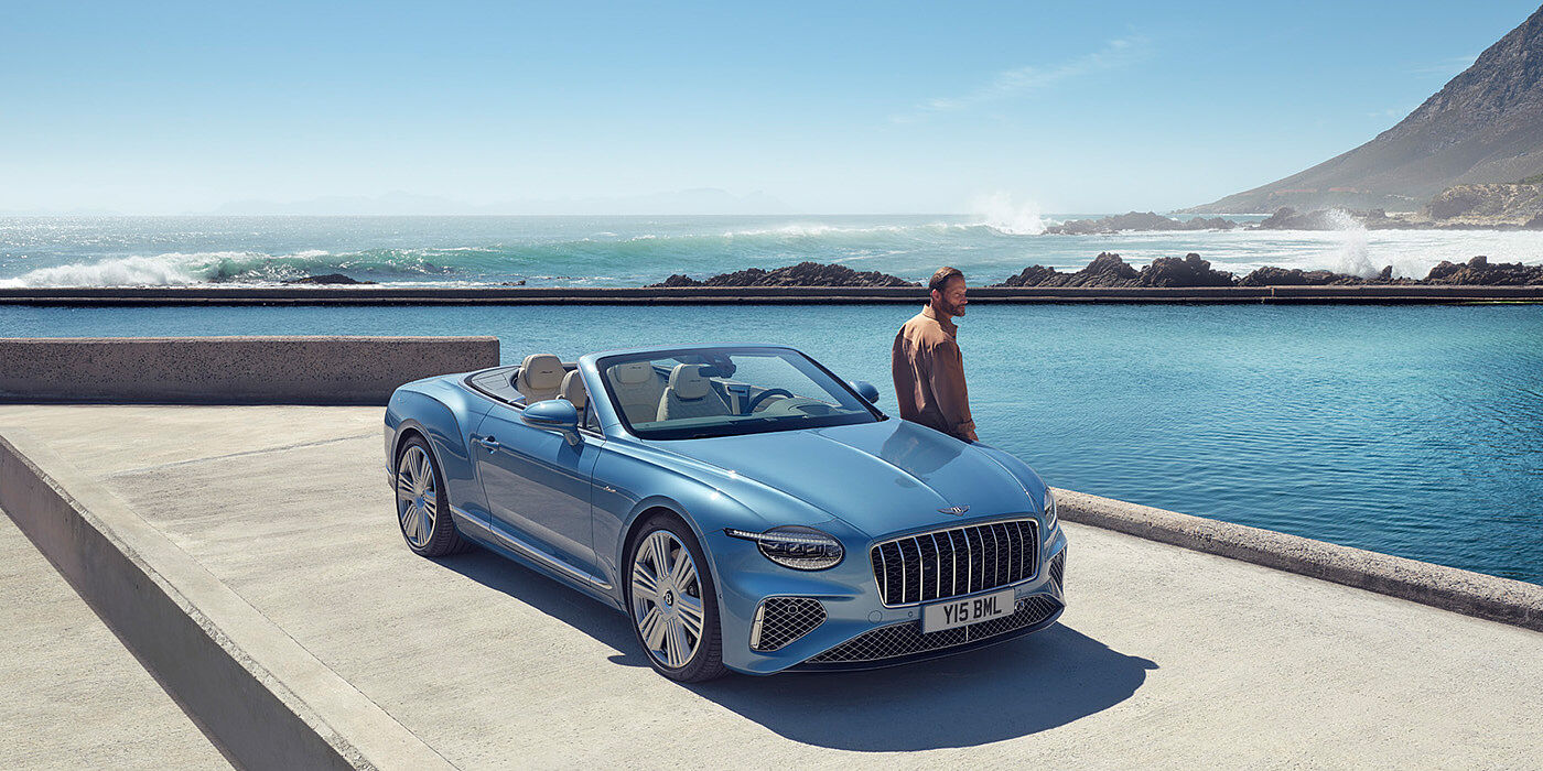 Bentley Lima New Bentley Continental GTC Azure convertible front view in Light Windsor blue paint with 22 inch ten spoke wheels parked by the sea in the sunshine