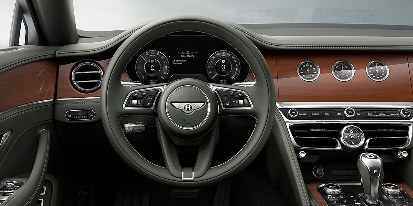 Bentley Lima New Bentley Flying Spur sedan front cabin in Cumbrian Green hide and Crown Cut walnut veneer showing steering wheel and Rotating Display with three clocks on face